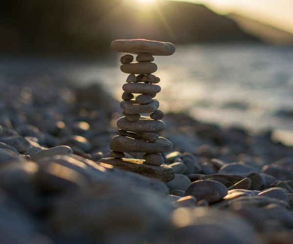 A balanced stack of stones on a beach at sunset, symbolizing harmony.