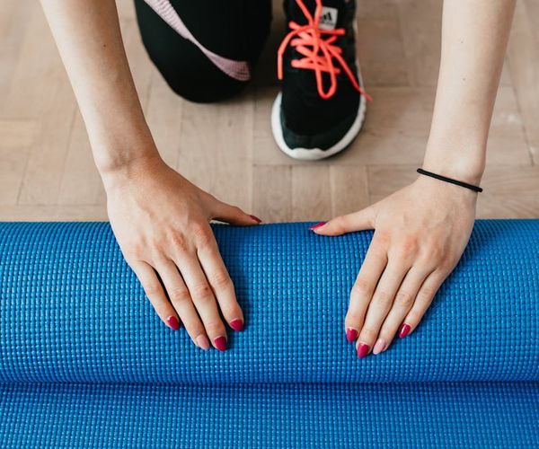 A rolled-up yoga mat on a wooden floor, ready for practice.